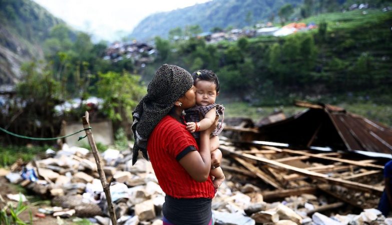 Uma nepalesa beija a filha em frente aos escombros da sua casa, em Baluwa, Nepal, depois do terremoto em 2015