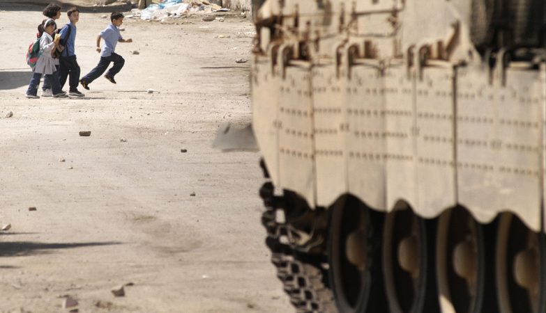 Crianças correm à frente de um tanque israelita em Nablus, na Palestina