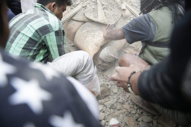 Populares em Katmandu tentam resgatar um homem dos escombros do sismo que atingiu o Nepal