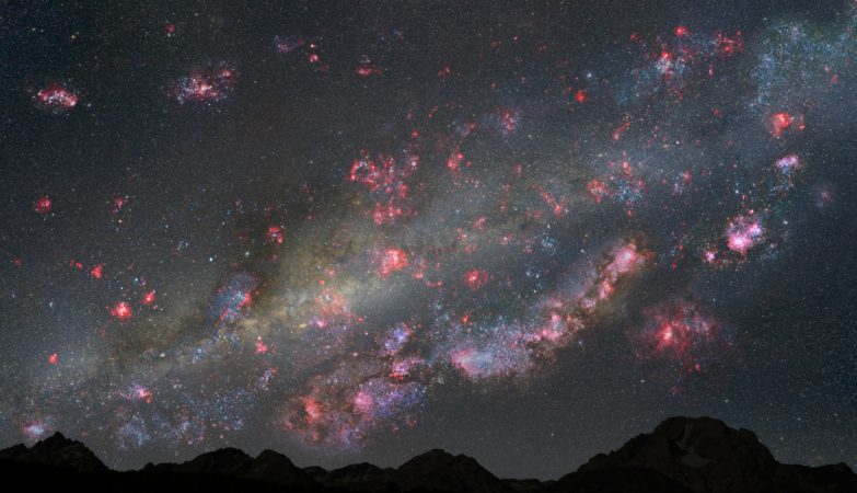 Impressão de artista do céu noturno a partir de um planeta hipotético dentro da uma jovem Via Láctea há 10 mil milhões de anos atrás, que mostra o céu a "arder" com formação estelar. As nuvens cor-de-rosa contêm estrelas recém-nascidas e os enxames de estrelas jovens azul-esbranquiçadas estão espalhados por toda a paisagem celeste.