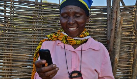 Uma agricultora na Tanzânia consulta o seu telemóvel