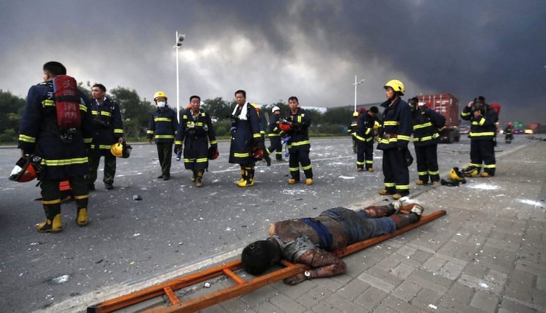 Bombeiros junto ao corpo de uma das vítimas das duas violentas explosões de Tianjin, na China