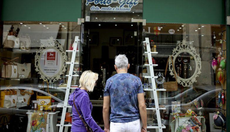Um casal de turistas observa a montra da Porto Gift, uma das muitas lojas de lembranças que surgiram no Porto com o aumento de visitantes