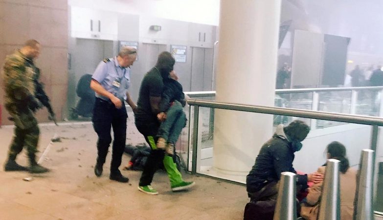 Alphonse Lyoura, ao centro, ajuda um ferido após uma explosão no aeroporto de Bruxelas