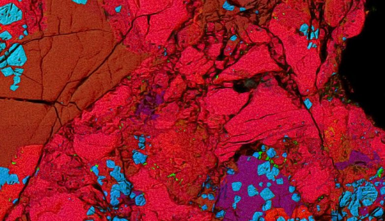 O meteorito carbonáceo Allende, salpicado com inclusões que têm uma química parecida com cerâmica (nesta imagem a cores falsas, vermelho para o cálcio, azul para o alumínio, verde para o magnésio). Quando estes elementos se formaram, as inclusões incorporaram cúrio-247 de curta duração (vida média de 15 milhões de anos), cujos traços foram detetados na pesquisa realizada na Universidade de Chicago como um excesso significativo de urânio-235, o produto do seu decaimento. O cúrio-247 vem da nucleossíntese nas estrelas que viveram e morreram antes do nascimento do Sistema Solar.
