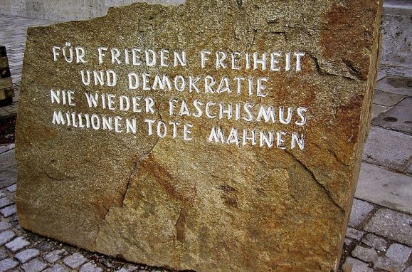 Monumento de pedra no lugar de nascimento de Hitler. A inscrição diz: "Pela paz liberdade / e democracia / fascismo nunca mais / milhões de mortos nos relembram."