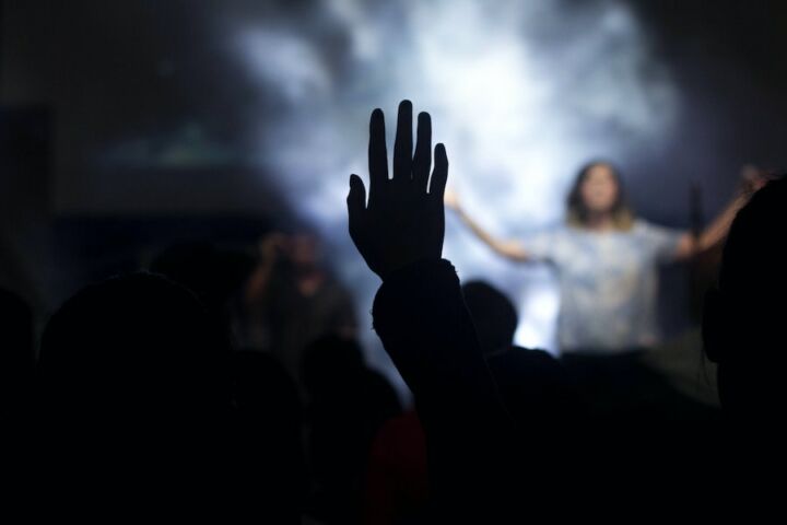 A silhueta da mão direita de uma pessoa no ar, enquanto vê um concerto