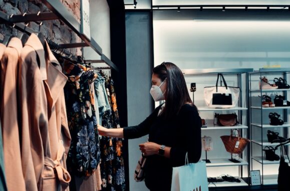 Uma mulher, a usar máscara, numa loja de roupa