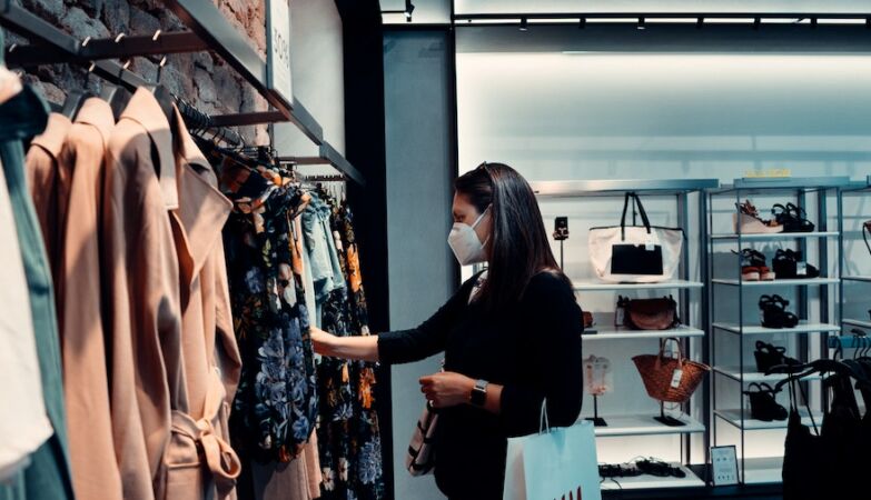 Uma mulher, a usar máscara, numa loja de roupa