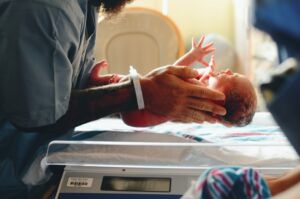 Um recém-nascido, ainda na maternidade, a ser pesado pela enfermeira