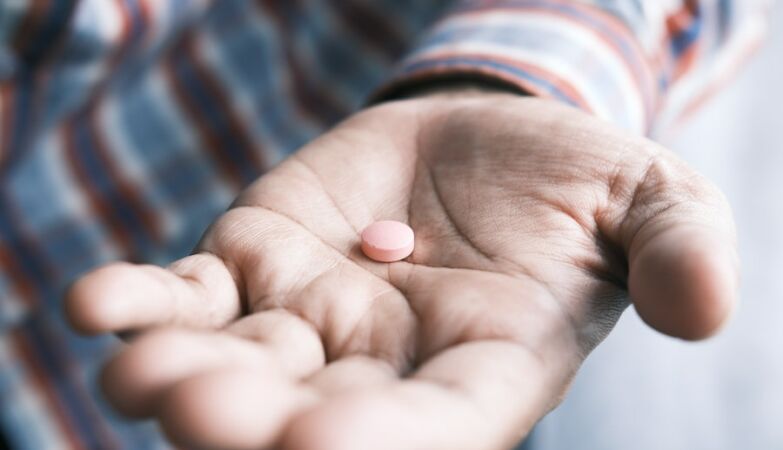 Um comprimido cor-de-rosa na mão de um homem
