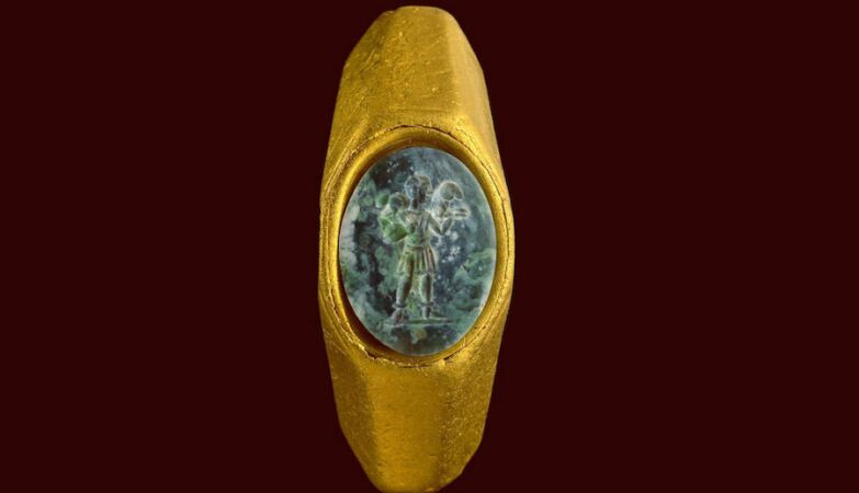 Anel de ouro com uma pedra preciosa verde e a figura do "Bom Pastor"