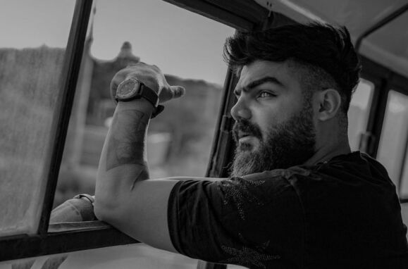 Homem com barba à janela numa foto do rapper Saman Yasin do Irão.