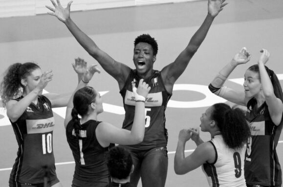Julia Ituma, jogadora de voleibol, com os braços levantados numa foto a preto e branco.