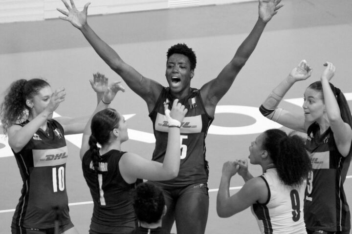 Julia Ituma, jogadora de voleibol, com os braços levantados numa foto a preto e branco.