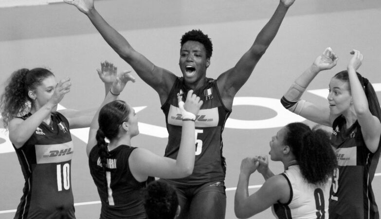 Julia Ituma, jogadora de voleibol, com os braços levantados numa foto a preto e branco.