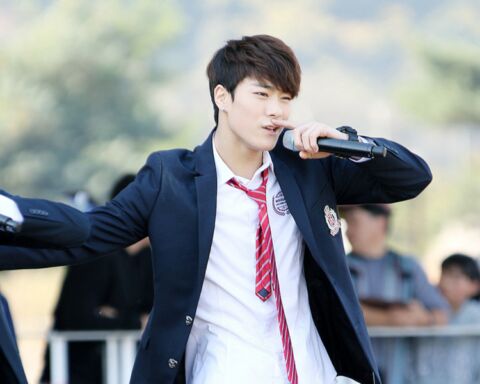 O cantor de k-pop Moon-bin a cantar de fato e gravata vermelha.