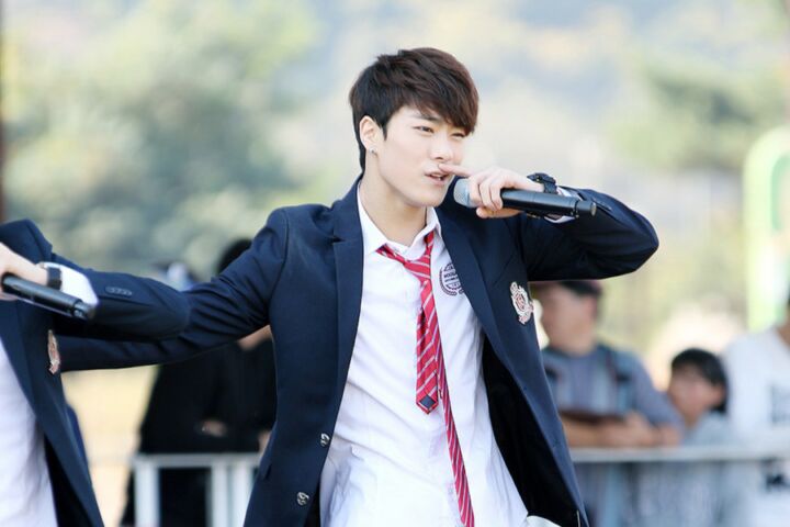 O cantor de k-pop Moon-bin a cantar de fato e gravata vermelha.