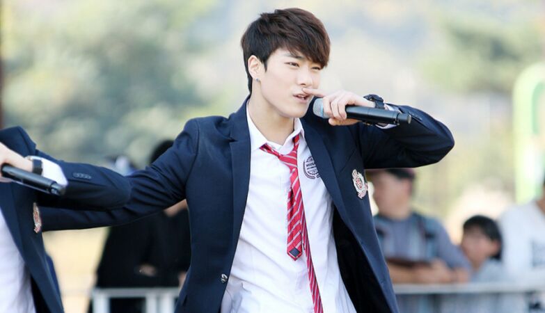 O cantor de k-pop Moon-bin a cantar de fato e gravata vermelha.