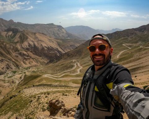 O motard português Nuno Castanheira de óculos a mostrar uma paisagem montanhosa no Irão.