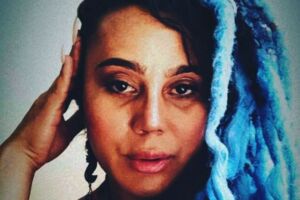 Rosto da actriz e activista transexual Keyla Brasil com rastas e o cabelo azul.