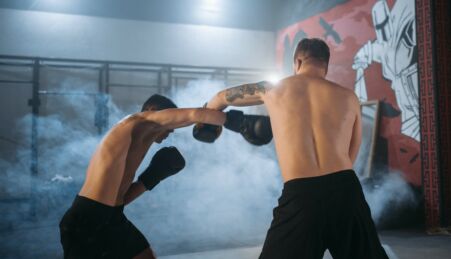 Lutadores de MMA - Artes Marciais mistas de calções pretos, sem camisola, e luvas de boxe a treinar.