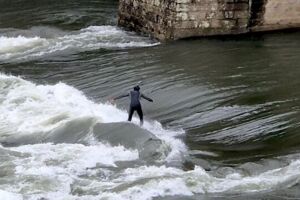 Jovem a fazer surf no rio Cávado em Barcelos, perto da ponte medieval.