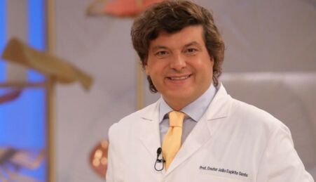 Dentista João Espírito Santo de bata branca e gravata amarela, a sorrir.