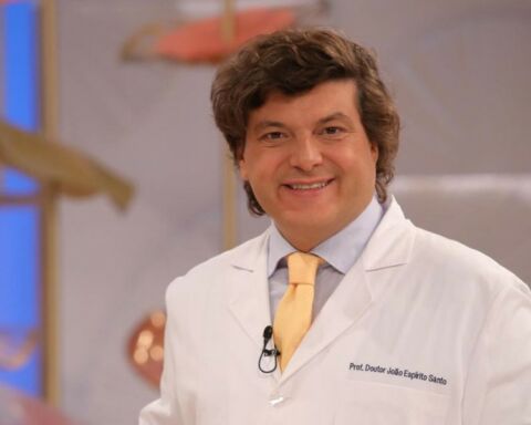 Dentista João Espírito Santo de bata branca e gravata amarela, a sorrir.