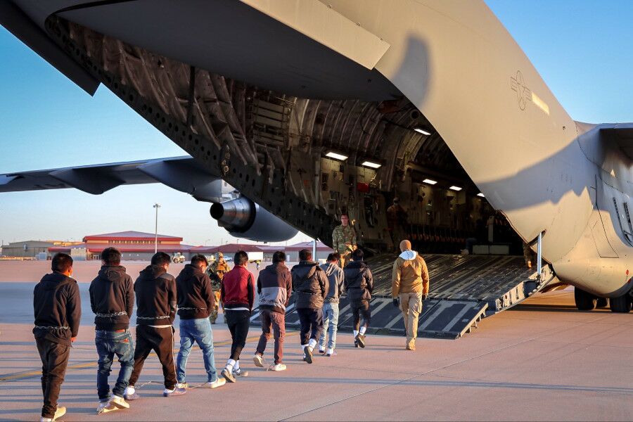 Imigrantes ilegais deportados dos EUA, entram num avião militar com as mãos e os pés algemados, e correntes em torno da cintura.