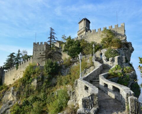 Paisagem em São Marino com castelo e muralhas no topo de montanha.