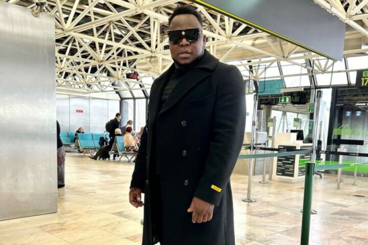 Cantor Américo Gomes de óculos escuros e vestido de preto num aeroporto.
